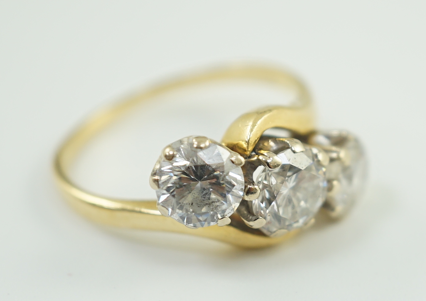 A modern 18ct gold and three stone diamond set crossover ring